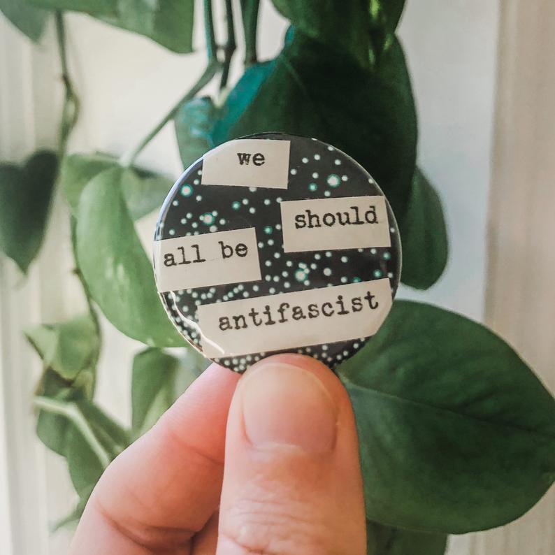 we should all be antifascist typed in typewriter font on a colorful background, 1.5 inch pinback button