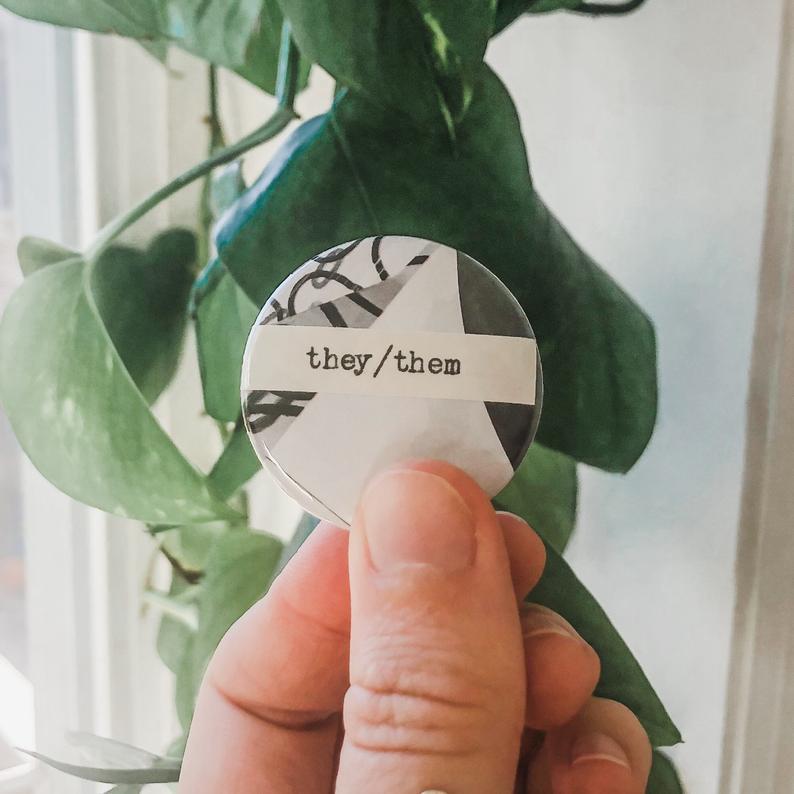 they/them pronouns typed in typewriter font on a colorful background, 1.5 inch pinback button 